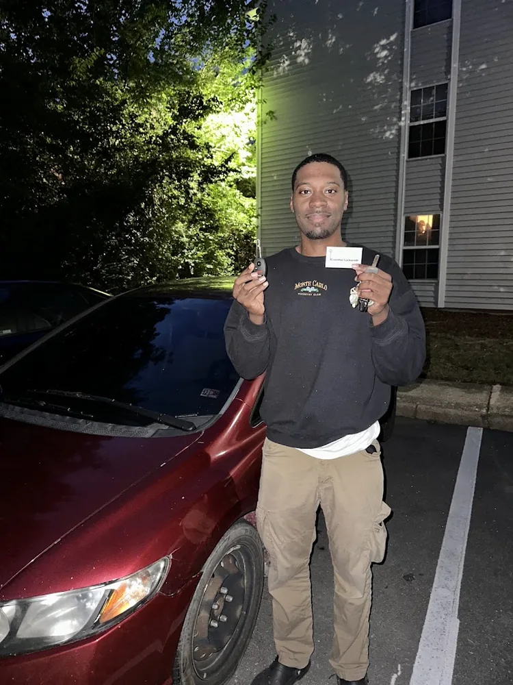 Customer holding a newly programmed car key and fob after dark